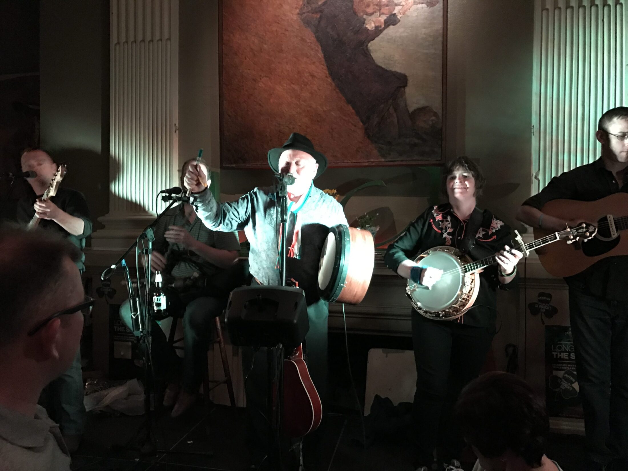 A traditional Irish band playing bodhran, banjo and guitar live on stage at The Plough and The Stars