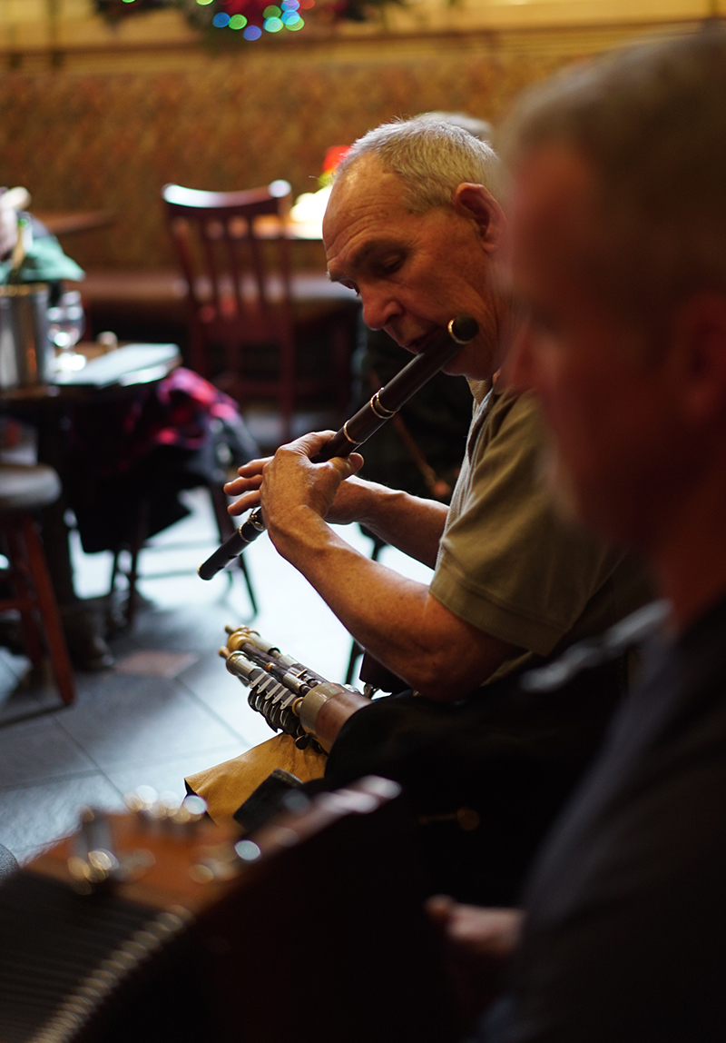 A musician playing the uilleann pipes during a session at The Plough and The Stars