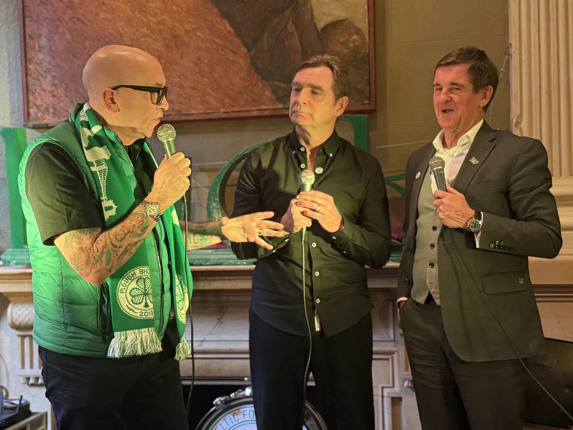 Guest speakers with microphones at a Celtic supporters event inside The Plough and The Stars