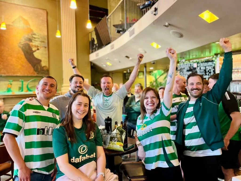 Celtic supporters in jerseys celebrating together at The Plough and The Stars